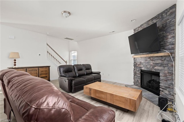 living room featuring light hardwood / wood-style floors and a stone fireplace