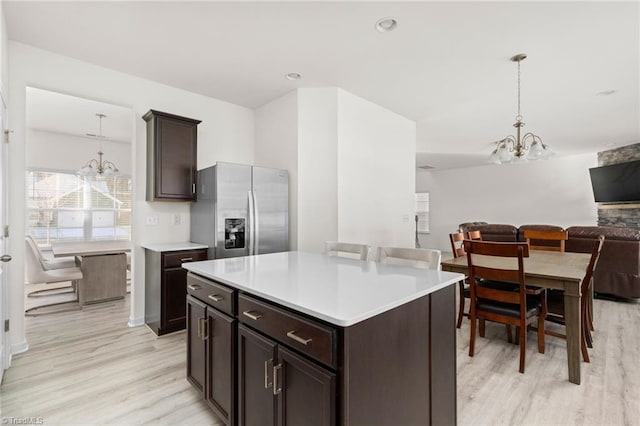 kitchen with a center island, an inviting chandelier, hanging light fixtures, dark brown cabinets, and stainless steel fridge with ice dispenser