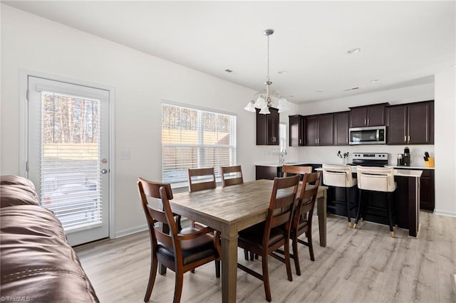 dining space featuring a notable chandelier and light wood-type flooring