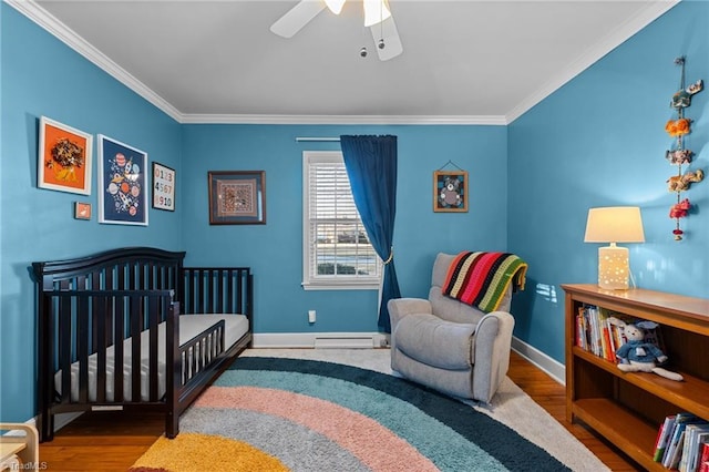 bedroom with a nursery area, ornamental molding, wood-type flooring, and a baseboard heating unit