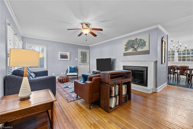 living room featuring hardwood / wood-style floors, crown molding, and ceiling fan with notable chandelier