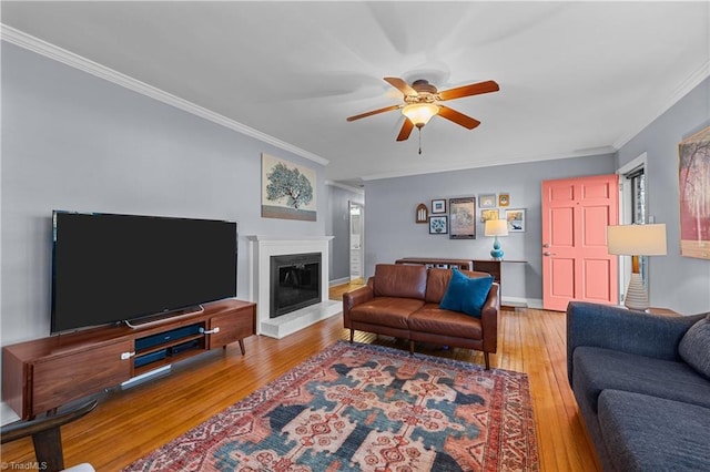 living room with ornamental molding, ceiling fan, and light hardwood / wood-style flooring