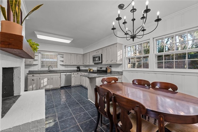 kitchen featuring sink, appliances with stainless steel finishes, an inviting chandelier, hanging light fixtures, and ornamental molding