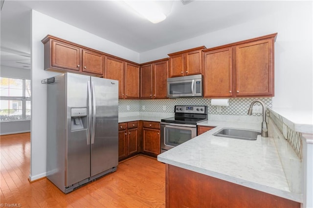 kitchen featuring tasteful backsplash, sink, light wood-type flooring, and appliances with stainless steel finishes