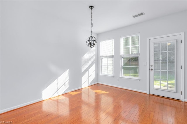 unfurnished dining area featuring hardwood / wood-style floors and an inviting chandelier