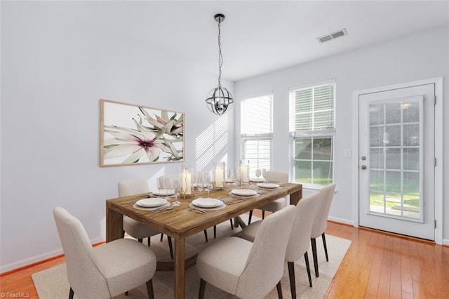 dining room with light wood-type flooring and a notable chandelier