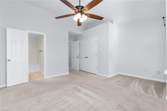 unfurnished bedroom featuring light colored carpet, vaulted ceiling, ceiling fan, connected bathroom, and a closet