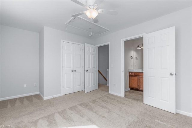 unfurnished bedroom featuring light carpet, a closet, ensuite bath, and ceiling fan