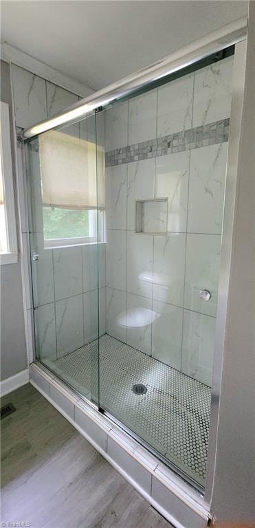 bathroom with hardwood / wood-style flooring and a shower with door