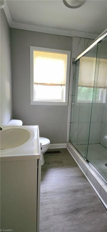 bathroom featuring hardwood / wood-style floors, vanity, ornamental molding, an enclosed shower, and toilet