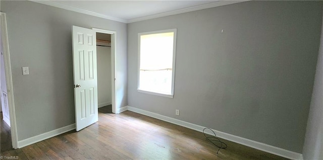 unfurnished bedroom with dark wood-type flooring, ornamental molding, and a closet