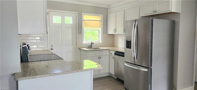 kitchen with appliances with stainless steel finishes, sink, white cabinets, backsplash, and ornamental molding