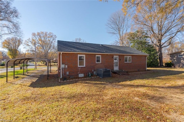 rear view of property featuring central air condition unit, a yard, and a carport