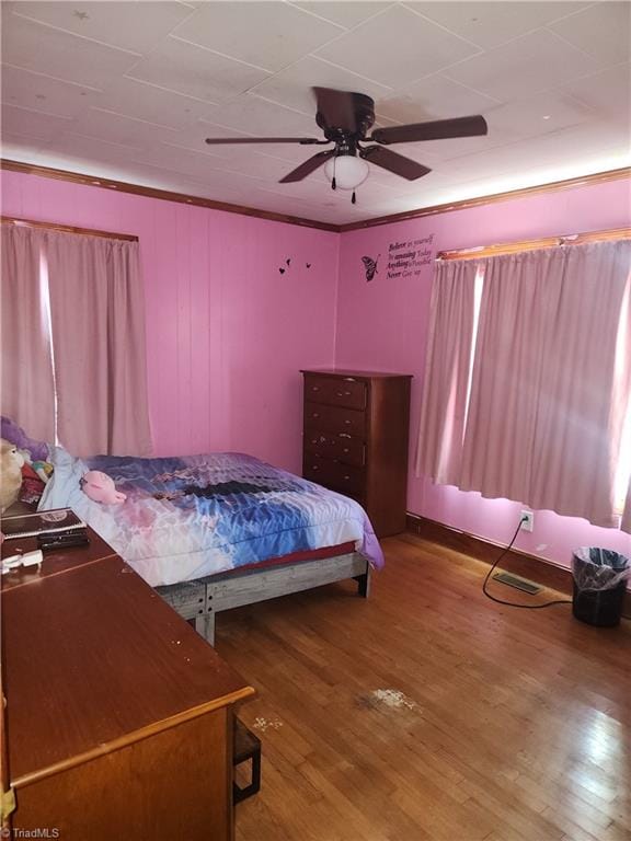 bedroom with ceiling fan, wood-type flooring, and ornamental molding