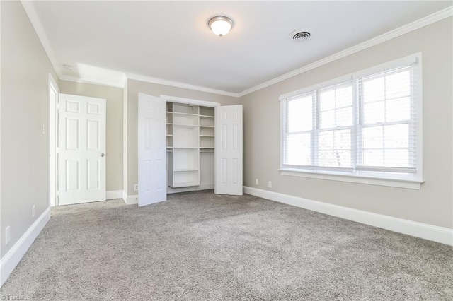 unfurnished bedroom featuring baseboards, visible vents, ornamental molding, a closet, and carpet flooring