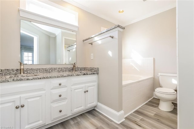 full bath with wood finished floors, double vanity, a sink, toilet, and a bathtub