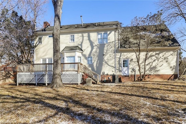 back of house featuring a lawn, central AC, a deck, and a chimney