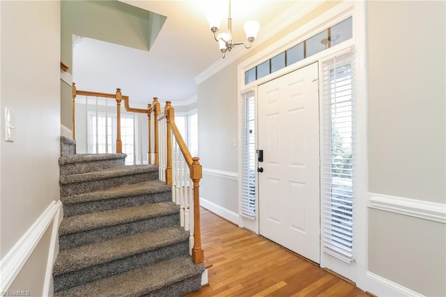 foyer featuring stairway, an inviting chandelier, light wood-style flooring, and crown molding