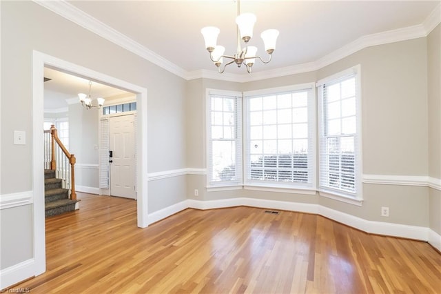 unfurnished dining area with stairway, plenty of natural light, light wood finished floors, and a chandelier