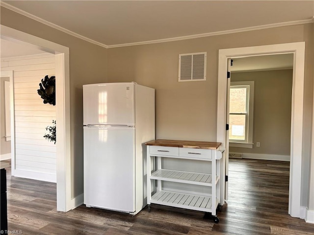 kitchen featuring visible vents, ornamental molding, dark wood finished floors, freestanding refrigerator, and wooden counters