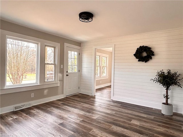 foyer entrance featuring dark wood finished floors, visible vents, baseboards, and ornamental molding