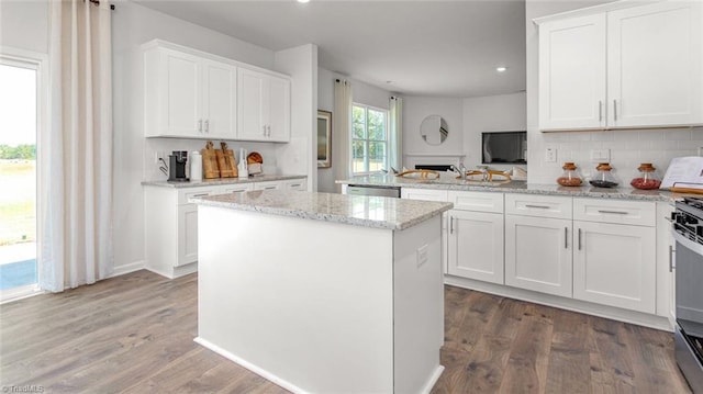 kitchen featuring white cabinetry, light stone countertops, hardwood / wood-style floors, and a kitchen island