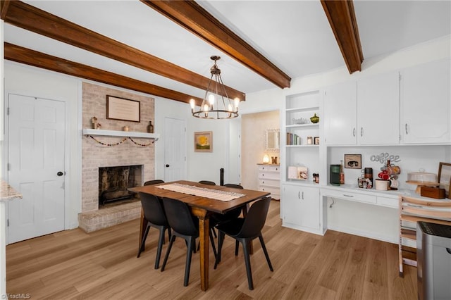 dining room featuring beam ceiling, a notable chandelier, light wood-style flooring, and a fireplace
