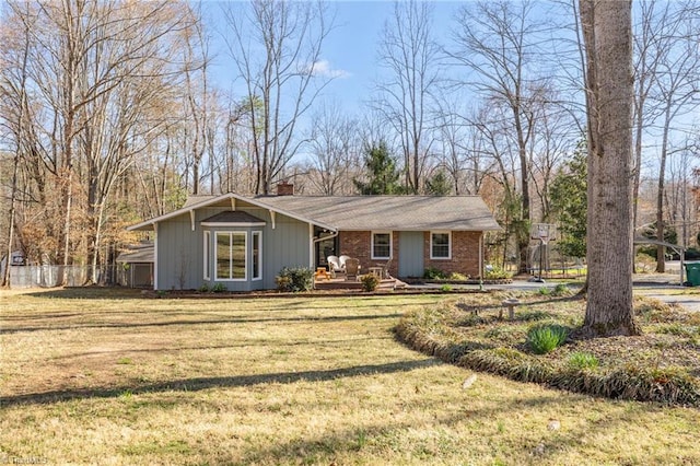 view of front of home with fence, a front yard, a chimney, brick siding, and a porch