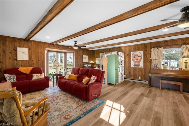 living room featuring ceiling fan, a healthy amount of sunlight, baseboard heating, and light wood-type flooring
