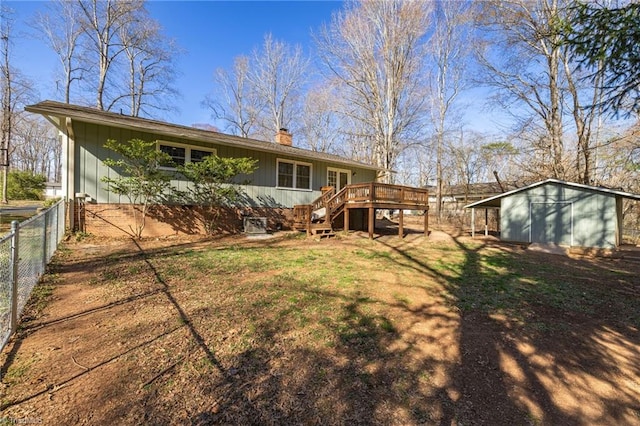 back of property with fence, a deck, stairway, a chimney, and a lawn