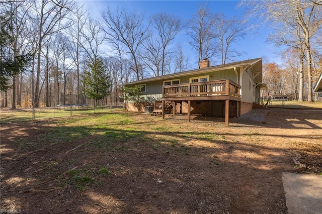 back of house featuring a chimney, a trampoline, a deck, fence, and stairs