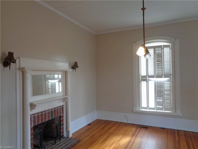 unfurnished living room featuring a healthy amount of sunlight, ornamental molding, a brick fireplace, and wood-type flooring