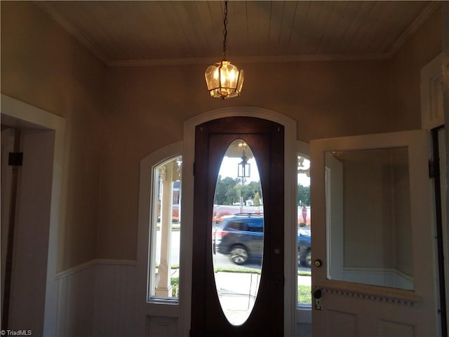 entryway featuring a wealth of natural light, ornamental molding, and an inviting chandelier