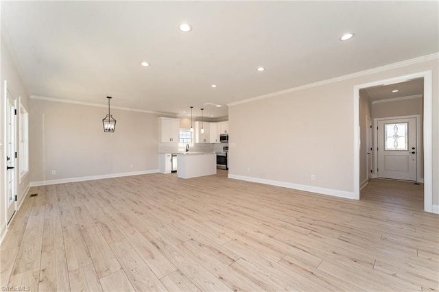 unfurnished living room featuring recessed lighting, baseboards, crown molding, and light wood finished floors