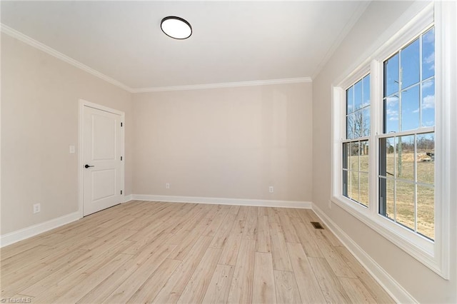 empty room featuring crown molding, light wood-type flooring, visible vents, and baseboards