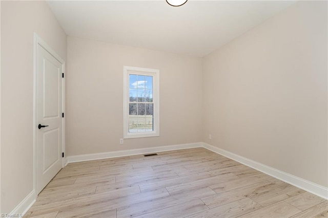 unfurnished room featuring light wood finished floors, visible vents, and baseboards