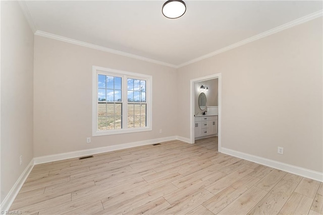 spare room with ornamental molding, visible vents, light wood-style flooring, and baseboards