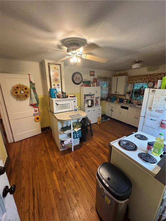 4679 S NC Highway 18, Moravian Falls, NC 28654 - kitchen with white appliances, dark wood finished floors, a ceiling fan, white cabinetry, and light countertops