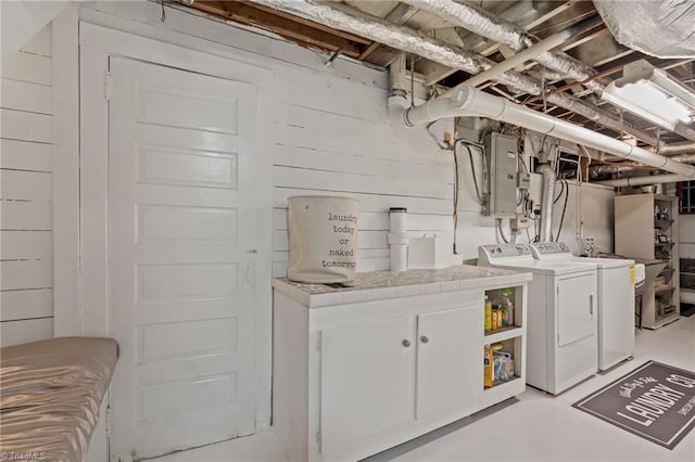 washroom with wooden walls, cabinets, separate washer and dryer, and electric panel