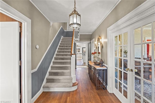 foyer entrance with dark wood-type flooring, crown molding, and french doors