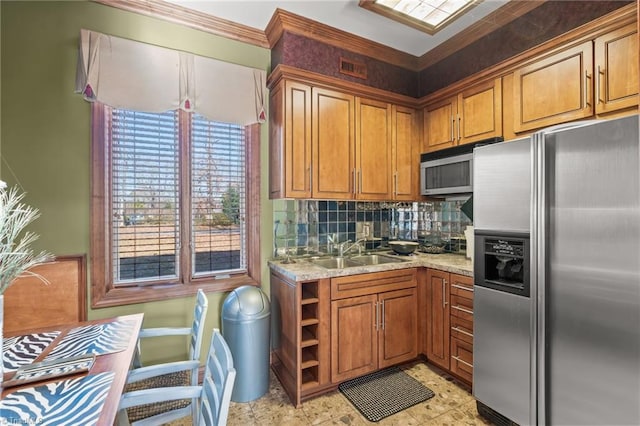 kitchen with light stone countertops, backsplash, stainless steel appliances, crown molding, and sink