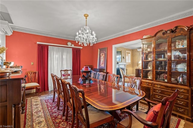 dining area featuring a healthy amount of sunlight, wood-type flooring, a chandelier, and ornamental molding