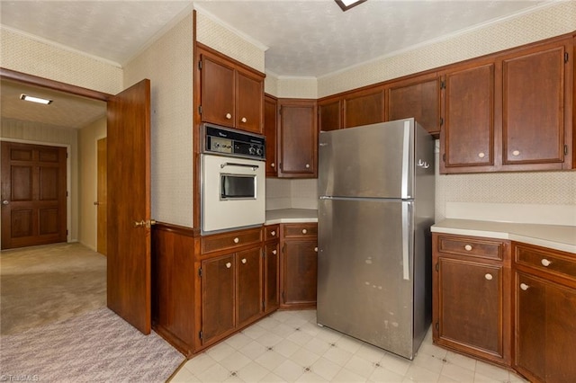 kitchen with crown molding, oven, stainless steel fridge, and light carpet