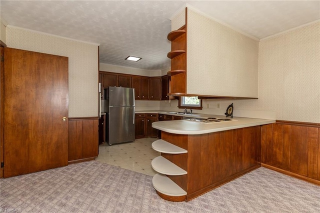 kitchen with white gas stovetop, stainless steel fridge, light tile patterned floors, kitchen peninsula, and sink