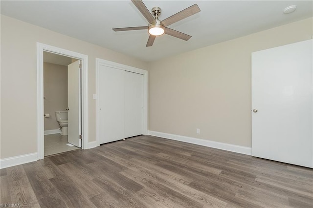 unfurnished bedroom with hardwood / wood-style flooring, ceiling fan, a closet, and connected bathroom