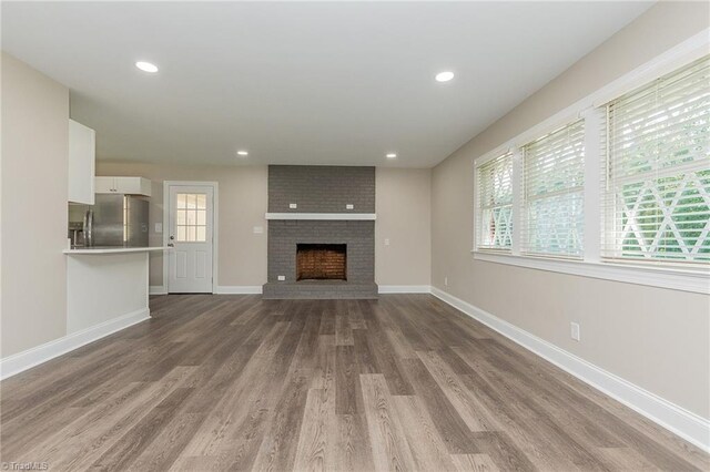 unfurnished living room with hardwood / wood-style flooring, a fireplace, and plenty of natural light