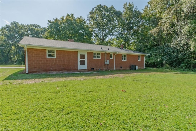 rear view of property featuring a lawn and central AC unit