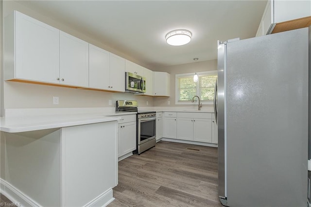 kitchen featuring white cabinets, stainless steel appliances, light wood-type flooring, and sink