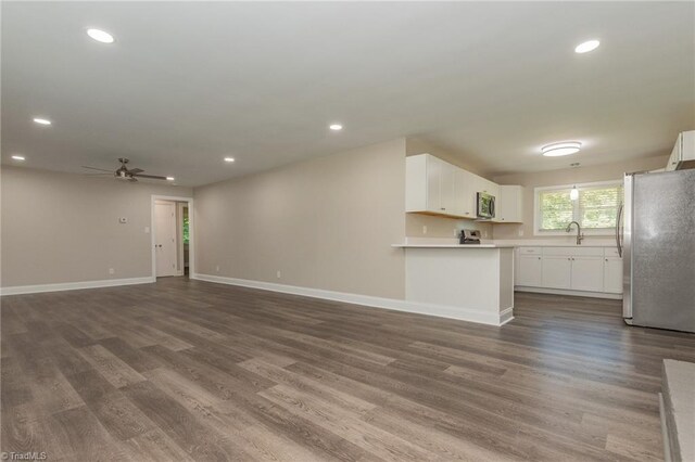 unfurnished living room with sink, ceiling fan, and dark hardwood / wood-style floors