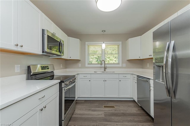 kitchen featuring decorative light fixtures, stainless steel appliances, dark hardwood / wood-style flooring, white cabinetry, and sink